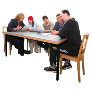 Five people sitting around a table discussing and reviewing papers.