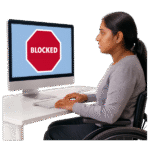Woman in wheelchair at a computer with a blocked message on the screen.