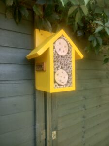 Yellow bee hotel this made from bamboo sticks and a recycled log with holes drilled out for bees to go inside.